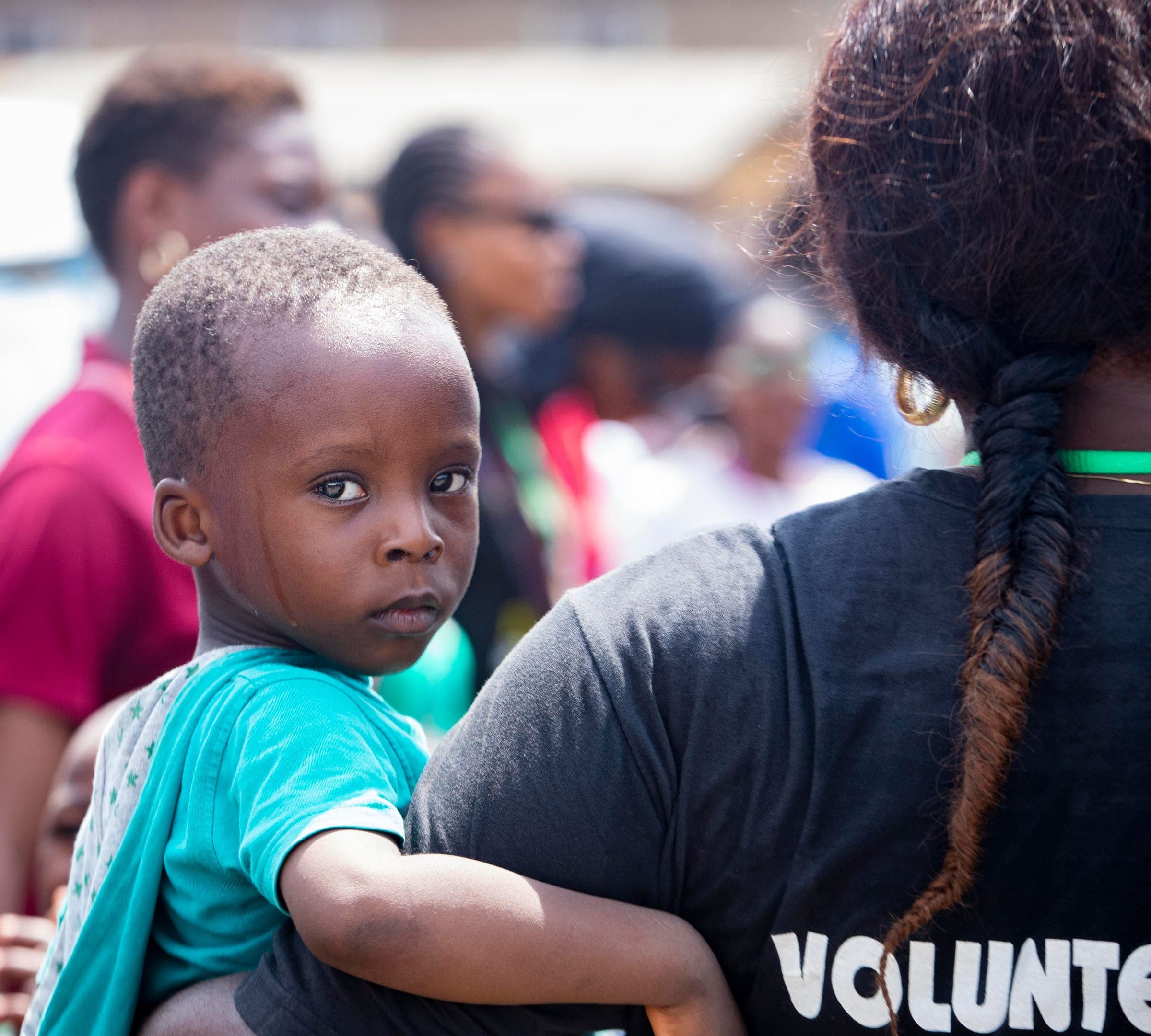 A young child held by a volunteer during a community event