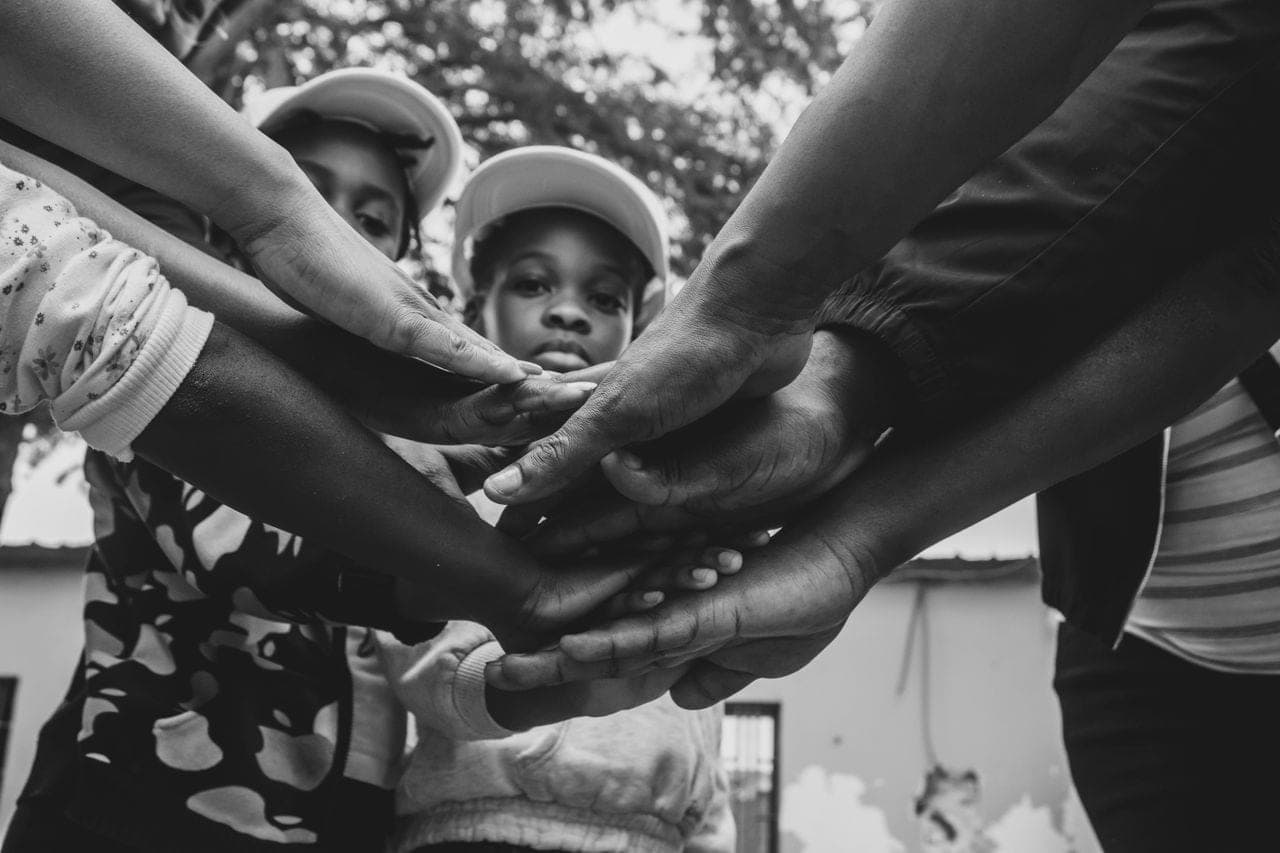 Children and adults stacking their hands together in a circle