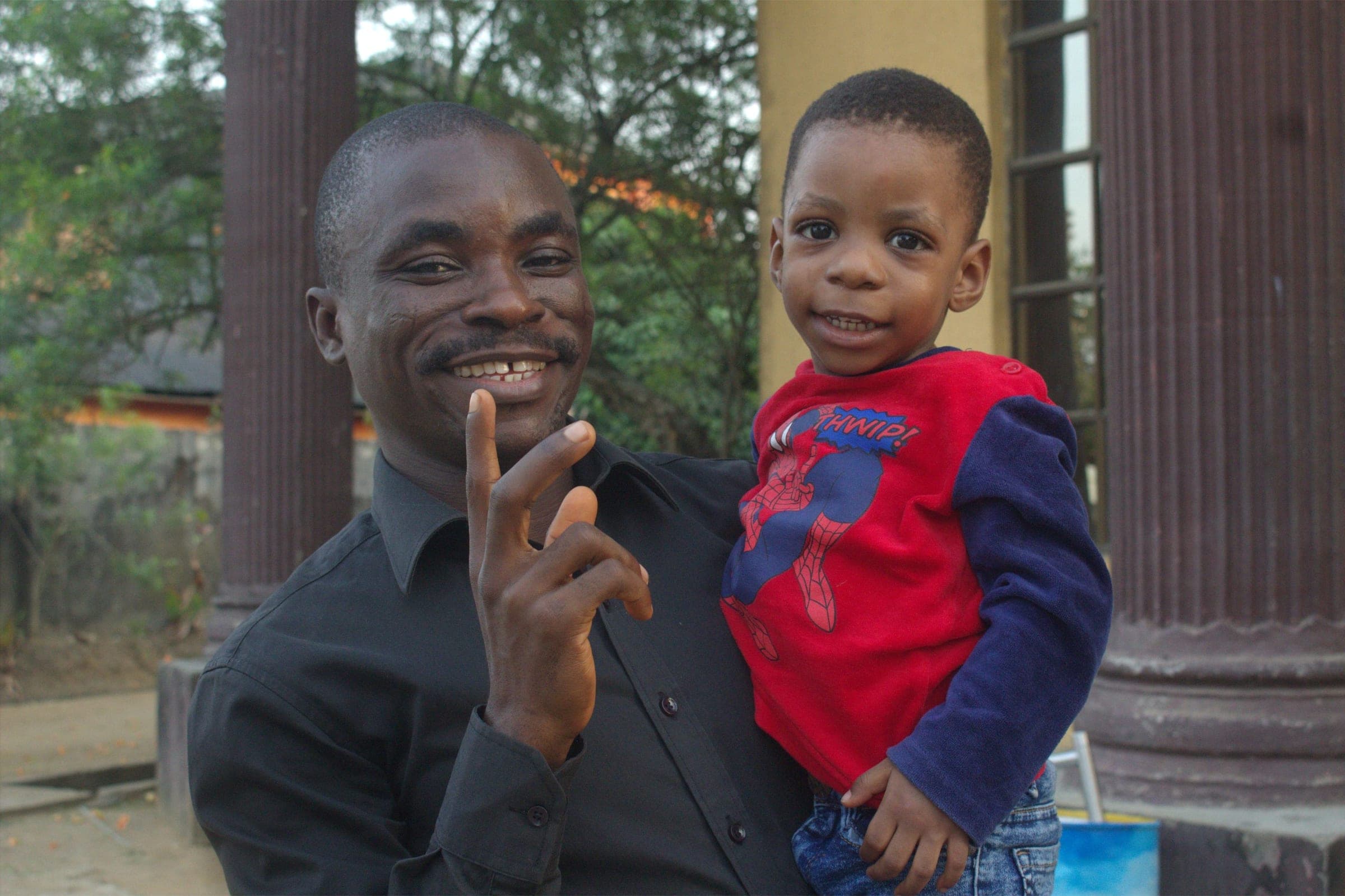 A smiling man holding a young boy