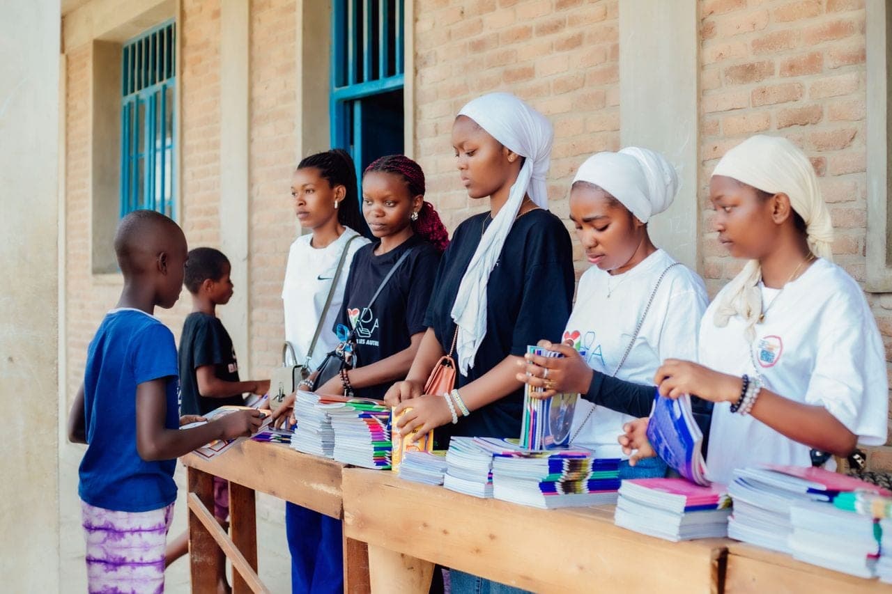 Volunteers handing out exercise books to school children