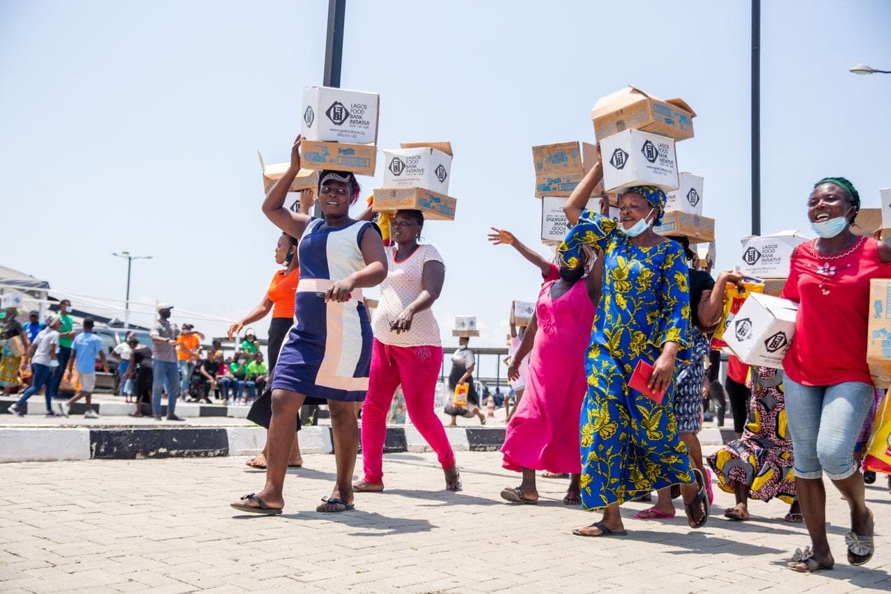 Women carrying boxes of food supplies on their heads after a distribution