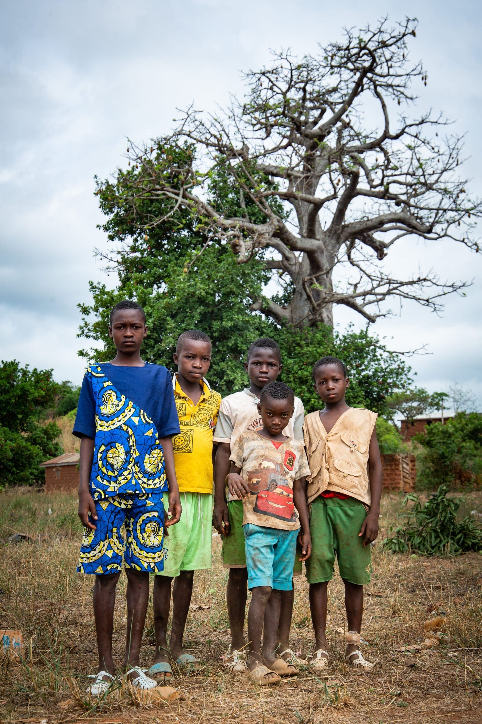 Five boys standing together in front of a baobab tree